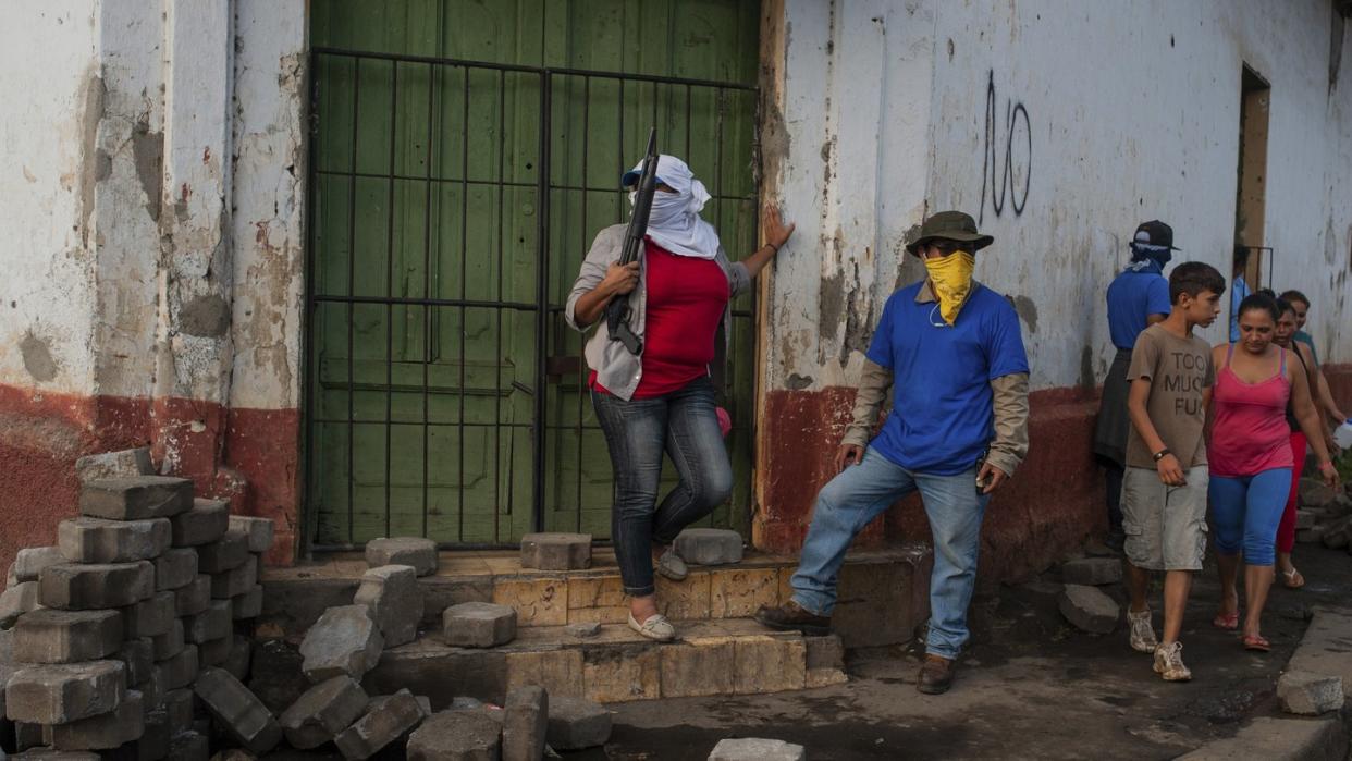 Milizen stehen neben einer niedergerissenen Barrikade, nach dem Pro-Regierungsmilizen und die Polizei die Nachbarschaft stürmten. Foto: Cristobal Venegas/AP