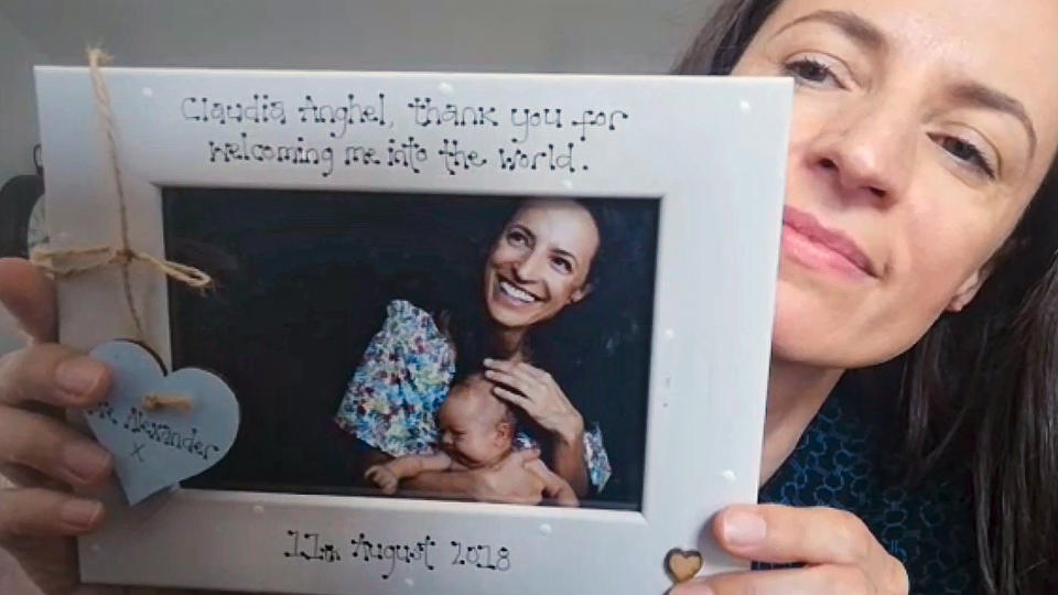 In this image taken from an online video interview with The Associated Press, Claudia Anghel, a Romanian midwife working in England, poses with a thank you card from a patient, in Nuneaton, England, Tuesday, July, 28, 2020. Anghel's success story as one of 600,000 Romanians in Britain is at the same time a telling sign of how the deficiencies of her home country's health care system and the bleak prospects for a better future for herself and her family have left huge gaps in Romanian society and its health care system. (AP Photo)