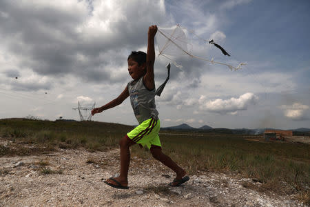 A Venezuelan indigenous boy of Pemon tribe flies a kite in the Brazilian indigenous village Tarau Paru in the border city of Pacaraima, Brazil April 12, 2019. Picture taken April 12, 2019. REUTERS/Pilar Olivares