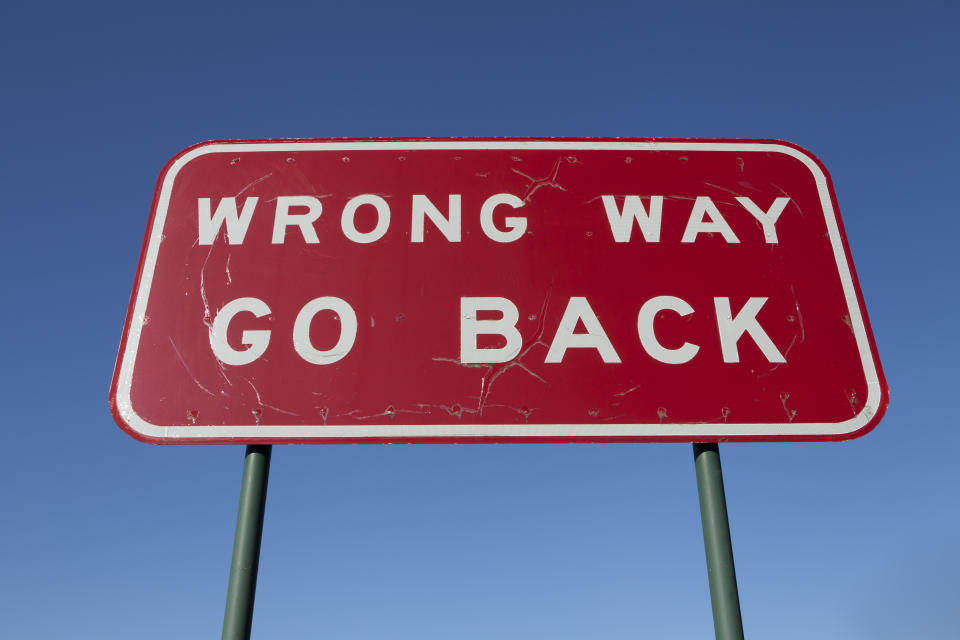 A road sign states "WRONG WAY GO BACK."