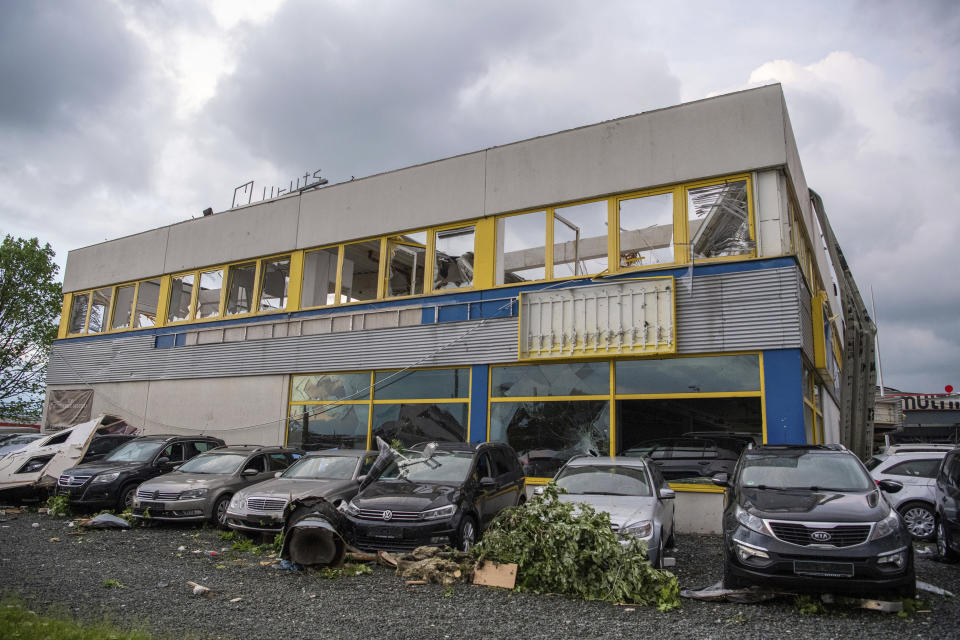 Parts of a roof hang over the facade of a car dealer from severe weather, in Paderborn, Germany, Friday, May 20, 2022. "In the course of a thunderstorm, a whirlwind on Friday afternoon cut a swath of devastation from west to east through the middle of Paderborn towards the eastern parts of the city," police said. (Lino Mirgeler/dpa via AP)