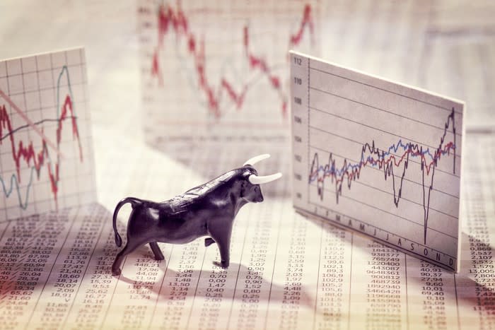 A bull figurine in front of a stock chart.
