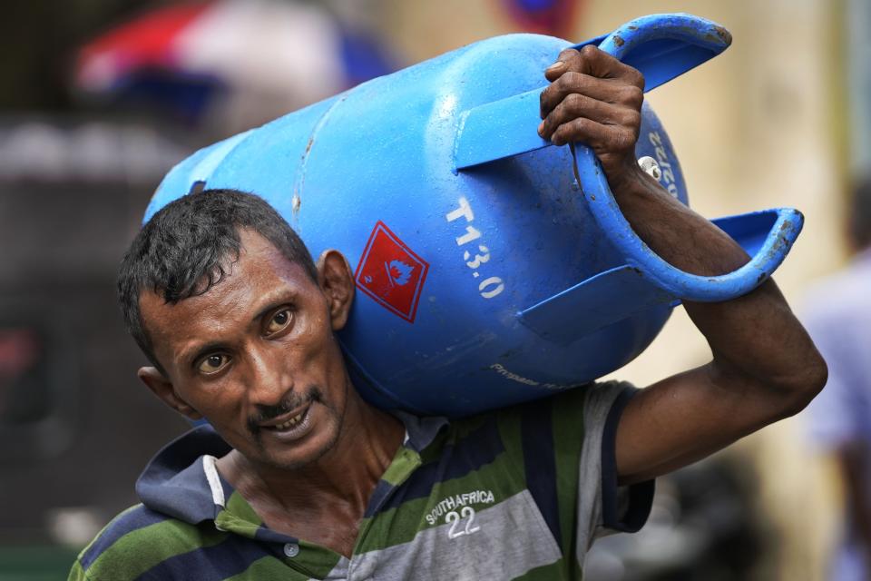 A man carries a cooking gas cylinder purchased from a distribution centre in Colombo, Sri Lanka, Saturday, May 14, 2022. Sri Lankans have been forced to wait in long lines to purchase scarce imported essentials such as medicines, fuel, cooking gas and food because of a severe foreign currency shortage. (AP Photo/Eranga Jayawardena)