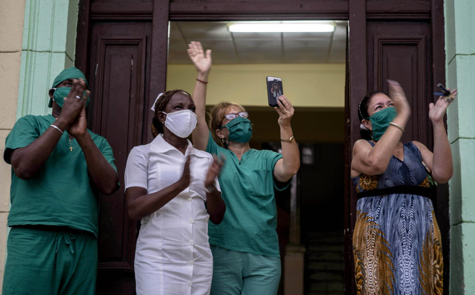 Personal médico aplaude al tenor cubano Andrés Sánchez Joglar, quien serena a sus vecinos desde el balcón de su apartamento en La Habana, el domingo 31 de mayo de 2020. El cantante de ópera está dando conciertos desde su casa todos los domingos por la tarde para animar a sus compatriotas en cuarentena durante la pandemia del coronavirus. (AP Foto/Ramón Espinosa)