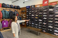 In this photo taken Wednesday, Aug. 28, 2019, Jennifer Lee, whose family owns Footprint shoe store in San Francisco, points to a wall of athletic shoes, many of which are made in China and will be subject to new U.S. tariffs on Chinese goods starting Sept 1. (AP Photo/Terry Chea)