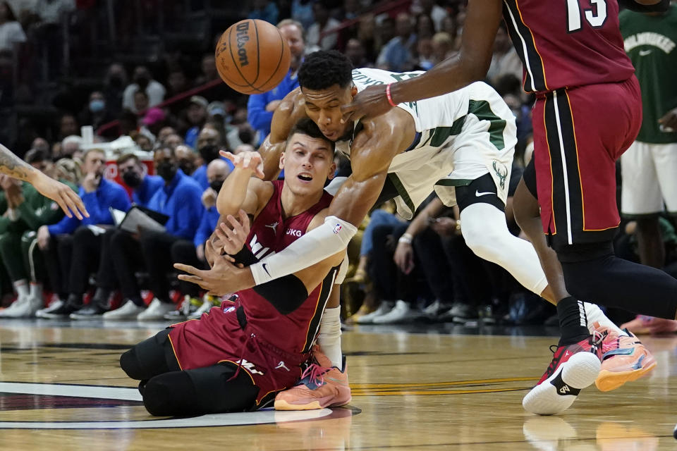 Miami Heat guard Tyler Herro, left, passes the ball as Milwaukee Bucks forward Giannis Antetokounmpo defends during the first half of an NBA basketball game, Thursday, Oct. 21, 2021, in Miami. (AP Photo/Lynne Sladky)