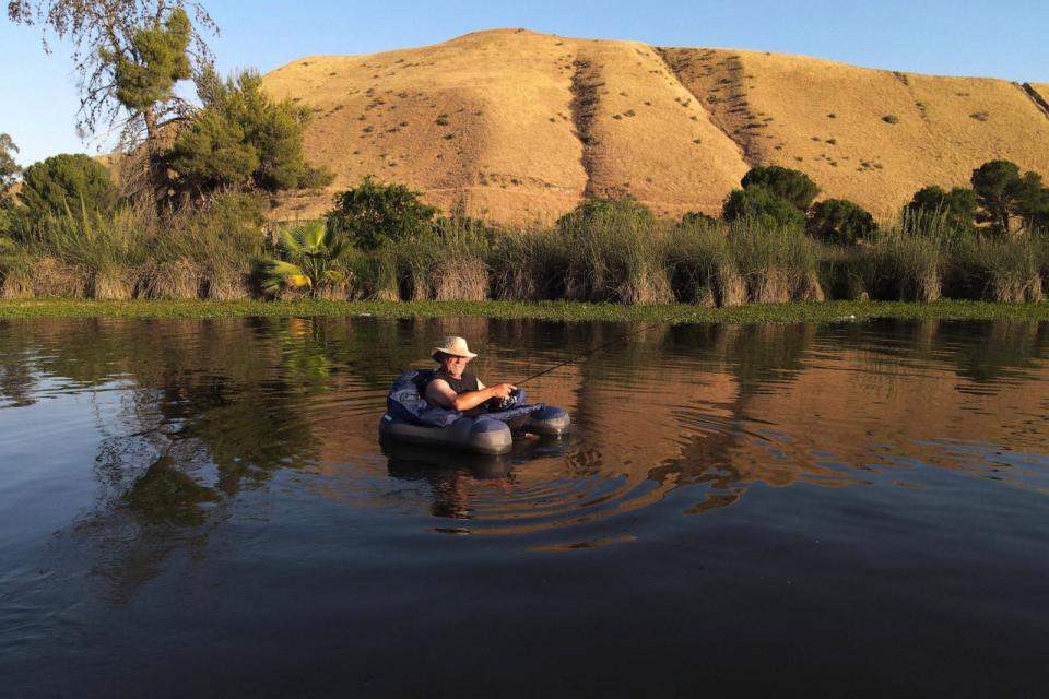 PHOTO: A fisherman finds relief from the over 100 degrees Fahrenheit temperature in the lake in Hart Memorial Park in Bakersfield, California, on June 5, 2024. (David Swanson/AFP via Getty Images)