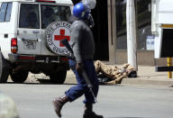 A red cross vehicle arrives to attend to an injured man during protests in Harare, Friday, Aug, 16, 2019. Zimbabwe's police patrolled the streets of Harare Friday morning while many residents stayed home and shops were shut fearing violence from an anti-government demonstration. Zimbabwe's High Court has upheld the police ban on the opposition protest.(AP Photo/Tsvangirayi Mukwazhi)