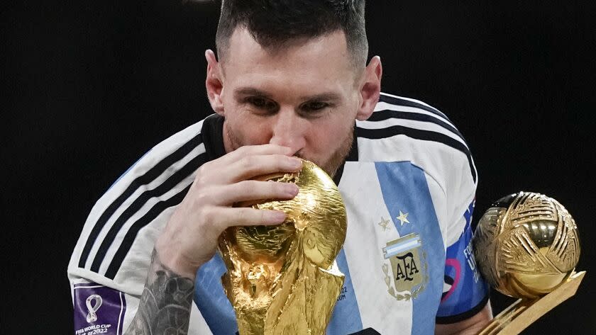 Argentina's Lionel Messi kisses the World Cup trophy with the golden ball trophy in his hand Dec. 18 in Lusail, Qatar.