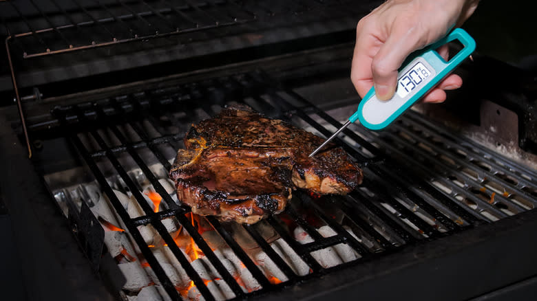 checking steak temperature on grill 