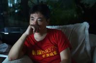 Jiang Hui, whose mother is among the passengers on missing Malaysia Airlines MH370, watches a recording of a TV news program about the discovery of part of an airplane wing on the French island of La Reunion, at his home in Beijing on July 31, 2015