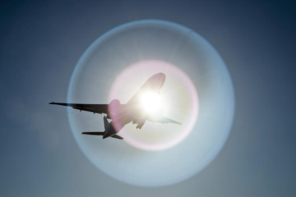 A Southern China Airlines flight from Guangzhou, China, causes a light flare on the camera lens as it flies past the sun as it arrives at Vancouver International Airport in Richmond, British Columbia, Wednesday, March 18, 2020. (Jonathan Hayward/The Canadian Press via AP)
