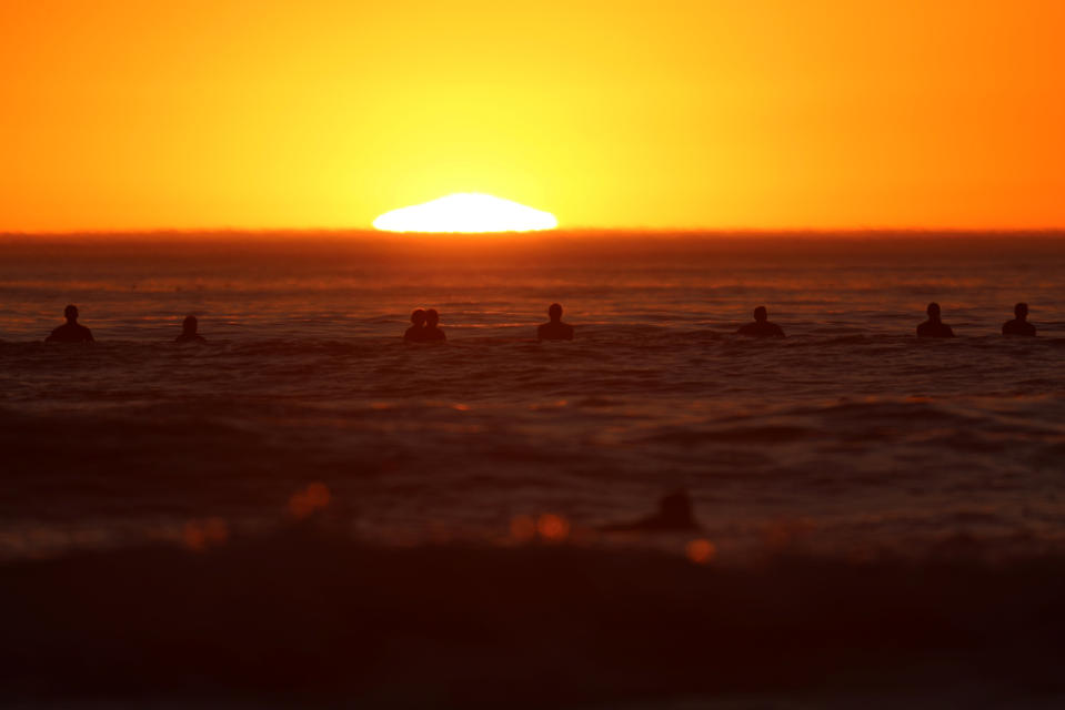 A group of surfers watch the sunset in Cardiff while waiting for the next set of waves during what local media reported to be a record breaking heat wave in Southern California, U.S., October 24, 2017. REUTERS/Mike Blake