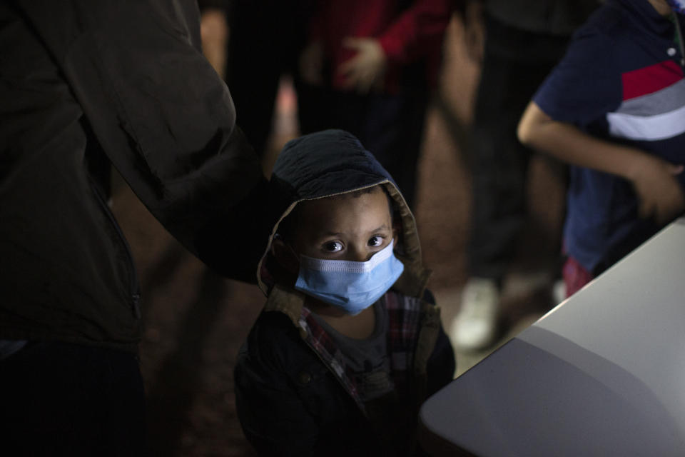 FILE - In this March 24, 2021, file photo, an unaccompanied minor looks up as he waits to answer questions from a U.S. Border Patrol agent at an intake site after he was smuggled on an inflatable raft across the Rio Grande river in Roma, Texas. Confronted with a stream of unaccompanied children crossing the border from Mexico, the U.S. government has awarded shelter-construction and management contracts to private companies that critics say may not be equipped to adequately care for the minors. (AP Photo/Dario Lopez-Mills, File)