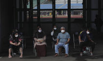 People wait to receive a shot of COVID-19 vaccine during a vaccination campaign at the Patriot Candrabhaga Stadium in Bekasi on the outskirts of Jakarta, Indonesia, Friday, Nov. 26, 2021. Indonesia has significantly recovered from a mid-year spike in coronavirus cases and deaths that was one of the worst in the region, but with its vaccination drive stalling and holidays approaching, experts and officials warn the island nation could be set soon for another surge. (AP Photo/Achmad Ibrahim)