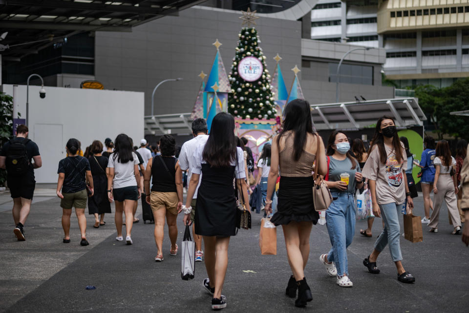 Crowds of people wearing protective face masks walk in Singapore's Orchard Road shopping district on Sunday, 12 December 2021. Singapore authorities reported on 15 December 2021, 2 persons with the Omincron variant of the Covid-19 virus who dined in restaurants along Orchard Road. (Photo by Joseph Nair/NurPhoto via Getty Images)