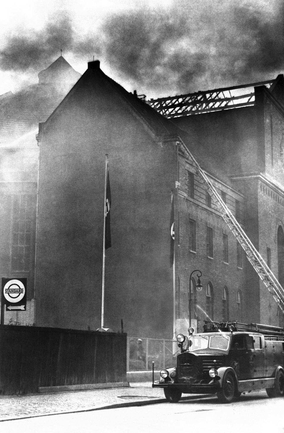 FILE - A fire truck with an extended ladder is parked on Prinzregenten Street in Berlin next to a synagogue that was set on fire on Nov. 10, 1938, during the organized Kristallnacht rampage carried out by Nazi paramilitary forces and German civilians over two days. During the violence perpetrators set fire to hundreds of synagogues, looted thousands of Jewish businesses and attacked Jews throughout Germany. The Conference on Jewish Material Claims Against Germany, also referred to as the Claims Conference, presents an interactive, virtual reality experience project to tell the story about the pogroms of the Kristallnacht or 'Night of broken glass'. (AP Photo, File)