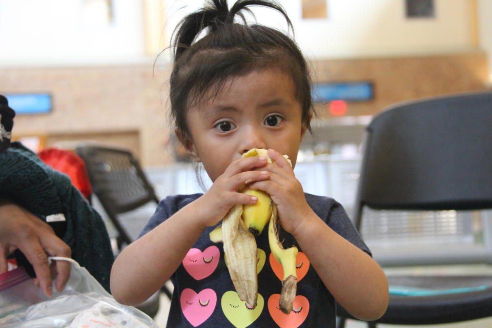 A Guatemalan child eats a banana at the Brownsville, Texas bus station shortly after being released from Border Patrol custody with her family.  / Credit: Natacha Larnaud