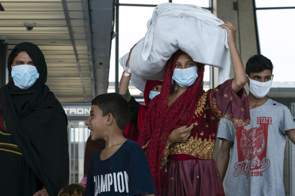 People evacuated from Kabul, Afghanistan, walk through the terminal before boarding a bus after they arrived at Washington Dulles International Airport, in Chantilly, Va., on Monday, Aug. 30, 2021. (AP Photo/Jose Luis Magana)