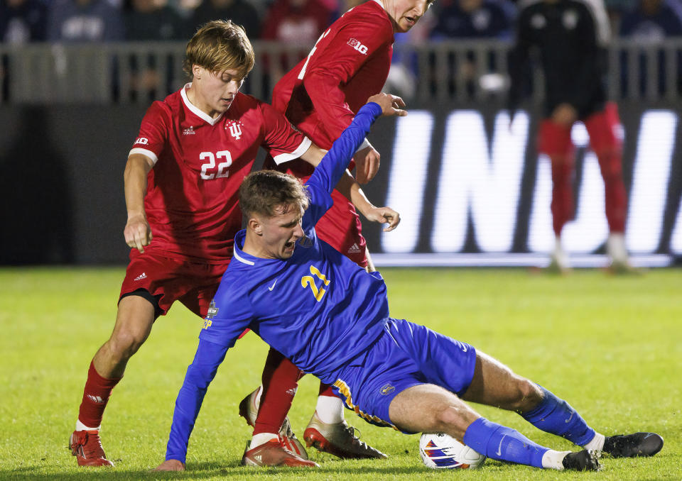 Pittsburgh's Filip Mirkovic (21) falls next to Indiana's Patrick McDonald (22) during the first half of an NCAA men's soccer tournament semifinal in Cary, N.C., Friday, Dec. 9, 2022. (AP Photo/Ben McKeown)