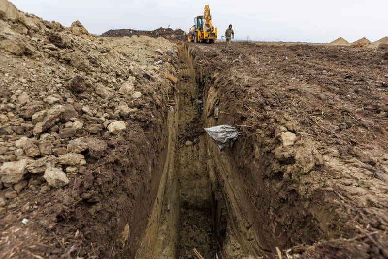 Croatian soldier is seen next to excavators during digging on newly discovered mass grave with 11 bodies near Vukovar