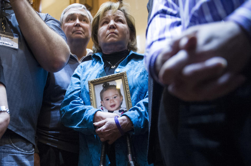 FILE - In a Tuesday, Jan. 28, 2014 file photo, medical marijuana advocate Barbara Kutchback, of Monroe, Ga., holds a photo of her 3-year-old granddaughter as she listens to other advocates tell of their children's suffering, after a bill to legalize marijuana for medicinal purposes was introduced in the State House chamber, in Atlanta. Kutchback's granddaughter suffers from a rare epilepsy disease and they believe marijuana can help relieve her suffering. In states where lawmakers are more likely to talk about the importance of Second Amendment rights and displays of the Ten Commandments, there is a serious effort underway to legalize medical marijuana. The push is gaining momentum in the Deep South, due in large part to heart-breaking stories of children suffering dozens of seizures a day whose parents say they would benefit from access to a type of cannabis oil.(AP Photo/John Amis, File)