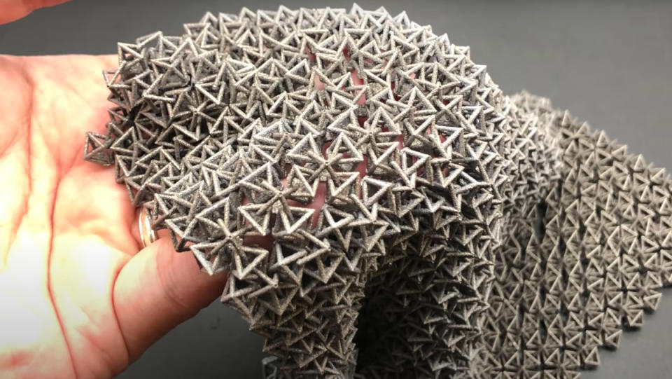 A hand holding a modern-day "chain mail" made of gray plastic.