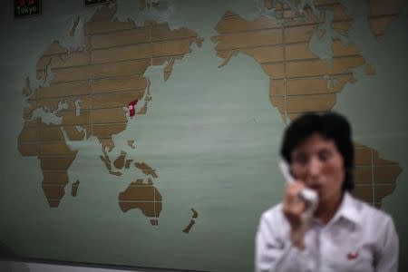 A world map, with the Korea peninsula marked in red, is seen as a hotel receptionist talks on the phone in Rason city, northeast of Pyongyang, August 29, 2011. REUTERS/Carlos Barria