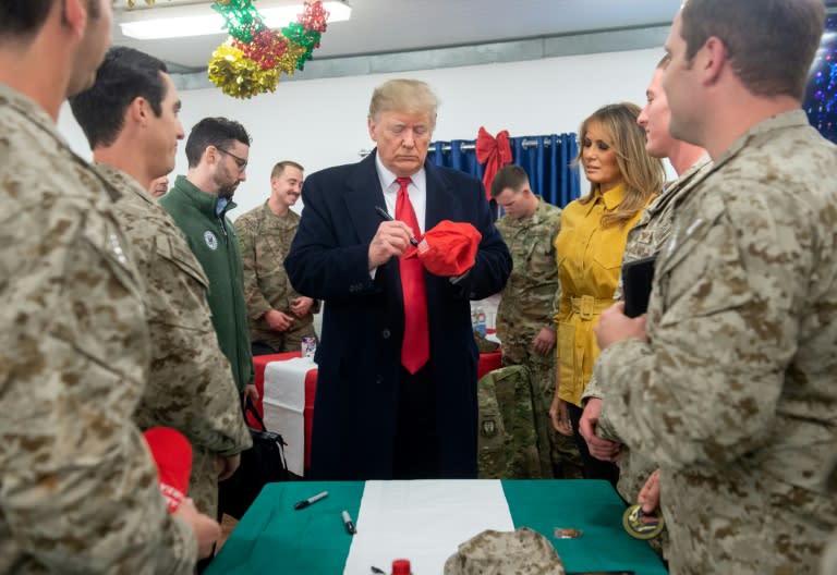 US President Donald Trump signs a hat as First Lady Melania Trump looks on while they greet members of the US military during an unannounced trip to Al-Asad Air Base in Iraq