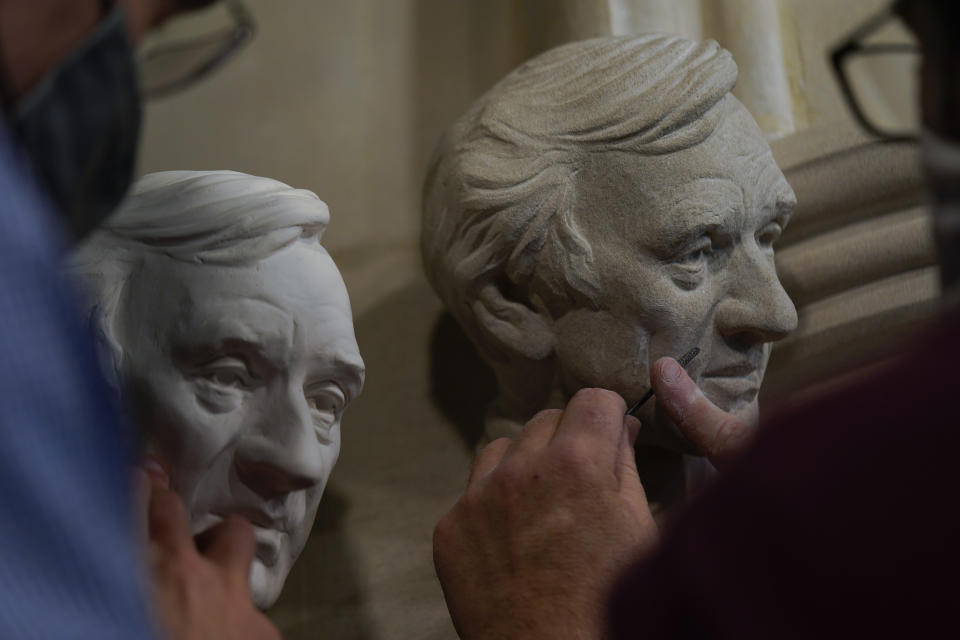 Artist Chas Fagan, left, works to fine tune his sculpture of Holocaust survivor and Nobel Peace Prize winning author Elie Wiesel with stone carver Sean Callahan in the Human Rights Porch of the Washington National Cathedral, Friday, April 16, 2021. (AP Photo/Carolyn Kaster)