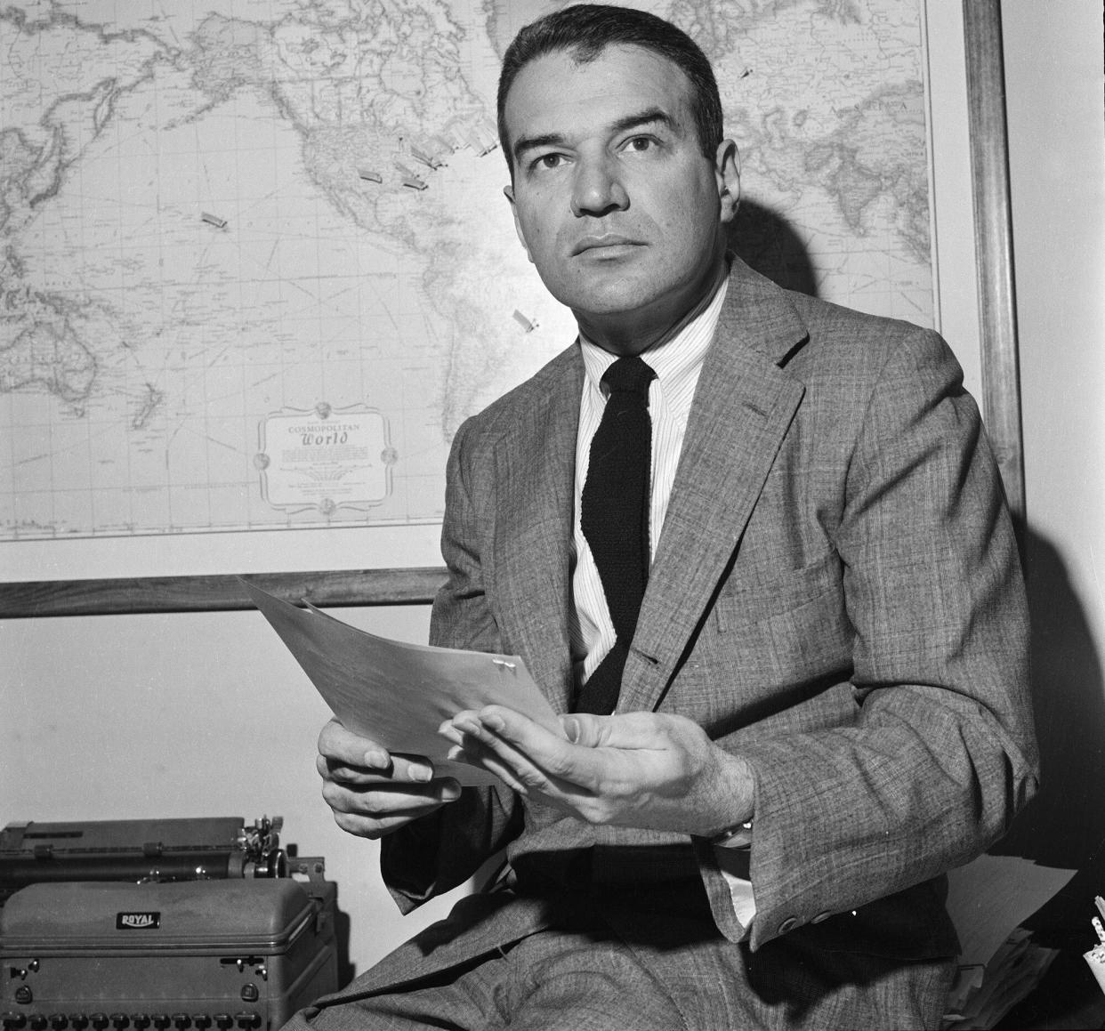 American news correspondent Bernard Kalb sits on the edge of a desk, a script in his hands, May 3, 1962.