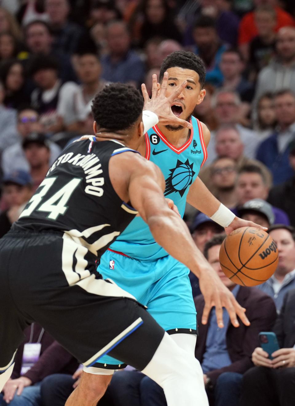 Milwaukee Bucks forward Giannis Antetokounmpo (34) guards Phoenix Suns guard Devin Booker (1) at Footprint Center in Phoenix on March 14, 2023.