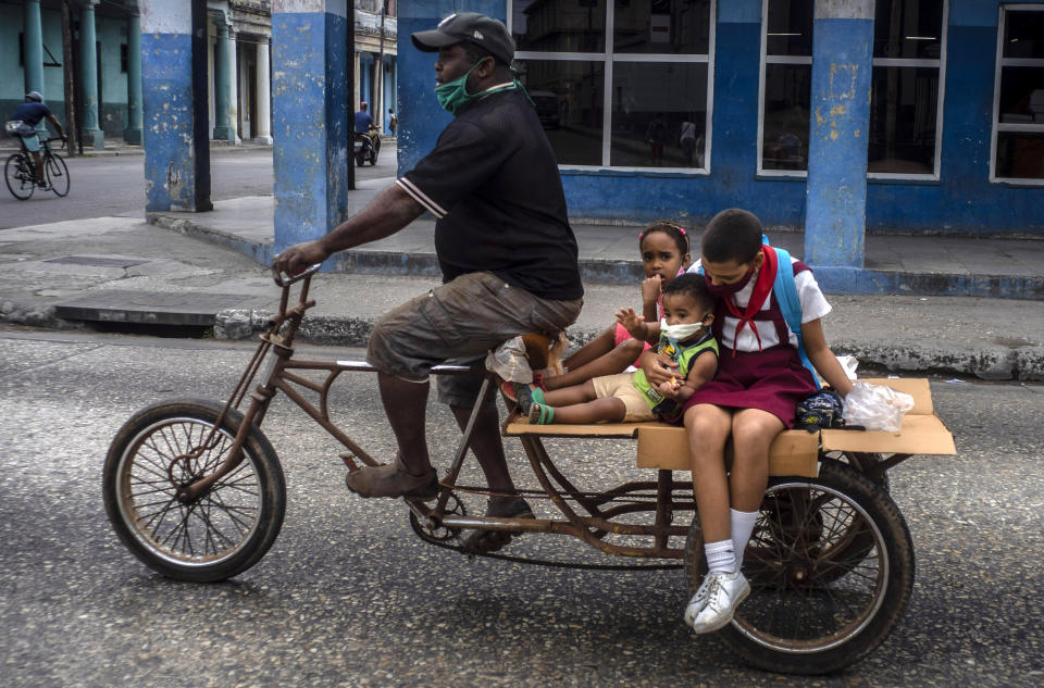 Un hombre transporta a niños en su triciclo el 8 de enero de 2021, en La Habana, Cuba. (AP Foto/Ramón Espinosa)