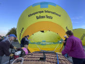 Crew members inflate a hot air balloon as part of a re-enactment of the first Albuquerque International Balloon Fiesta in 1972 during a special event at Coronado Center in Albuquerque, New Mexico, on Friday, Sept. 30, 2022. Hundreds of hot air balloons will be lifting off over the nine-day annual fiesta that has drawn pilots and spectators from across the globe for 50 years. (AP Photo/Susan Montoya Bryan)