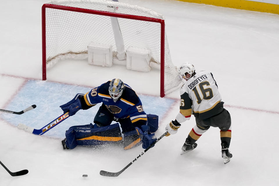 St. Louis Blues goaltender Jordan Binnington (50) and Vegas Golden Knights' Pavel Dorofeyev reach for a loose puck during the second period of an NHL hockey game Sunday, March 12, 2023, in St. Louis. (AP Photo/Jeff Roberson)