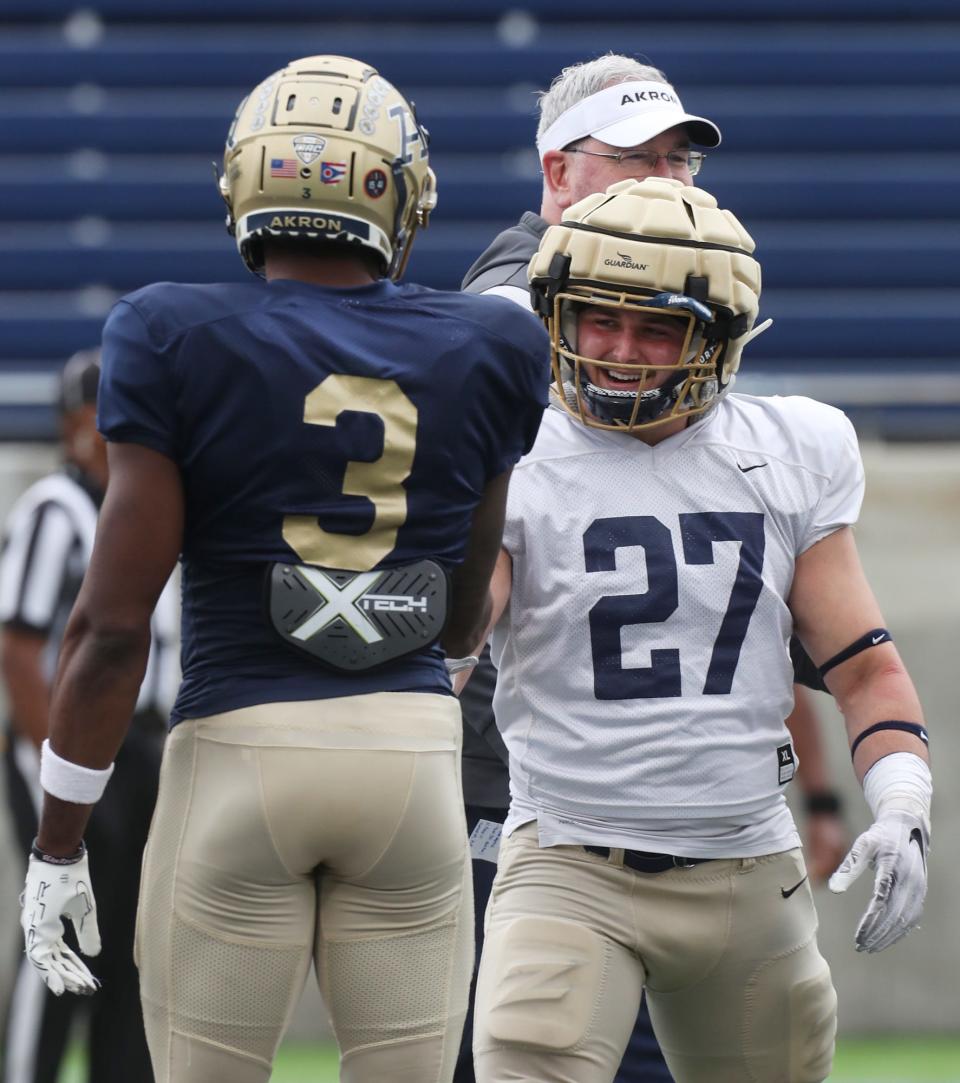 Akron wide receiver Daniel George shakes hands with linebacker Bubba Arslanian after the coin toss at the start of the 2023 spring football game Saturday.