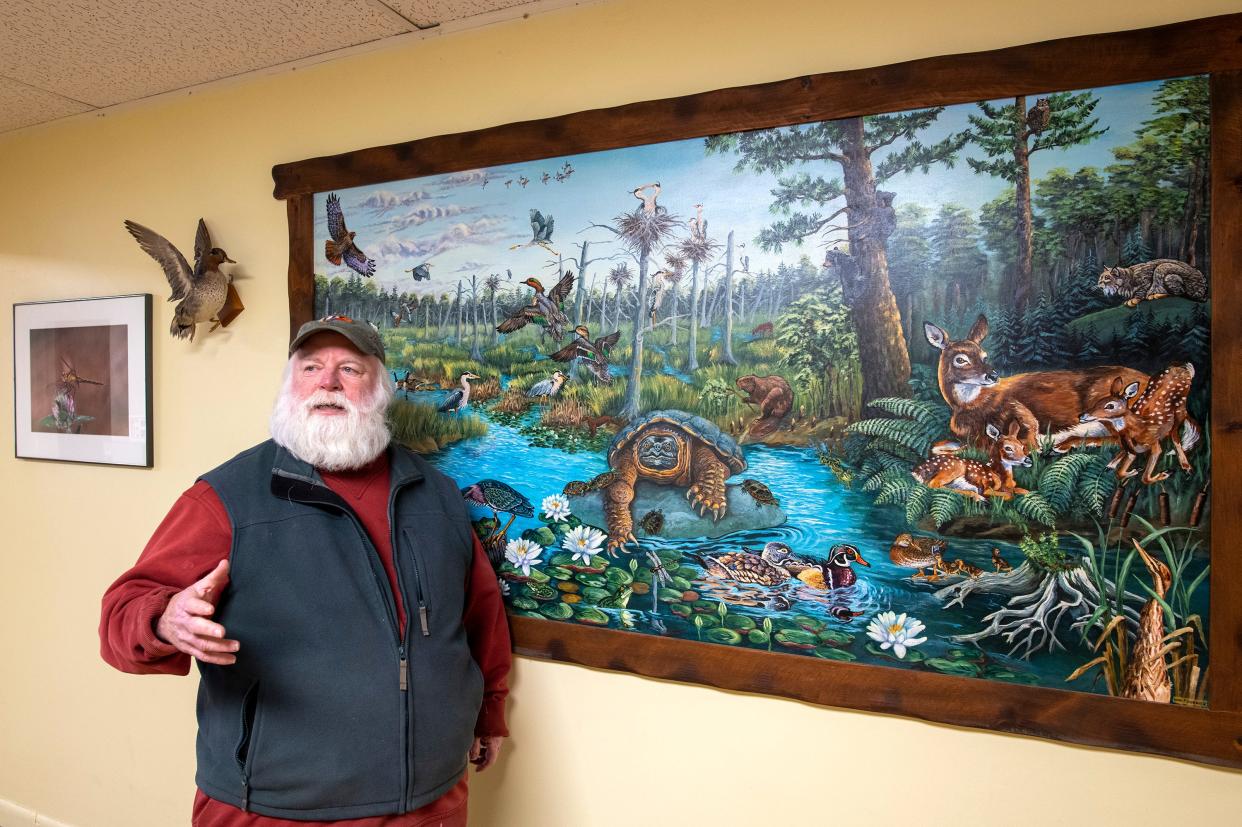 Athol Bird & Nature Club President Dave Small describes the many species portrayed on a mural in the club.