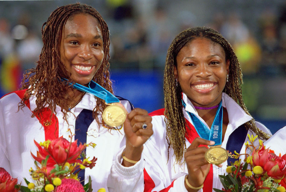 Venus and Serena smiling and holding up their medals
