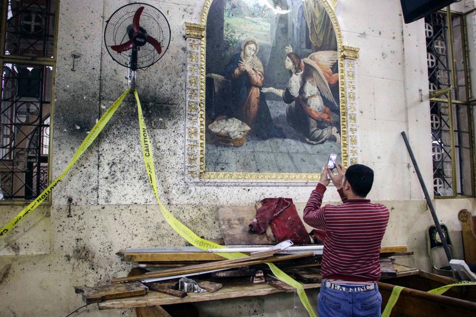 An Egyptian man uses his cell phone to take pictures of the destruction, debris, and bloodstains on the walls and icon murals inside the Mar Girgis Coptic Orthodox Church in the Nile Delta City of Tanta.