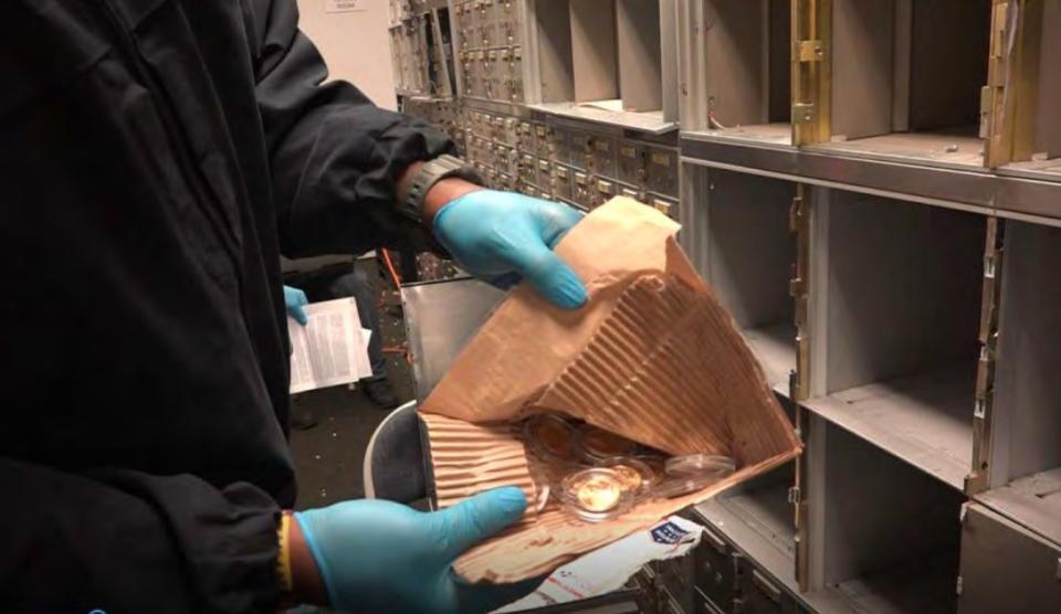 An agent open a sealed envelope that appear to contain coins during the raid of U.S. Private Vaults in Beverly Hills.