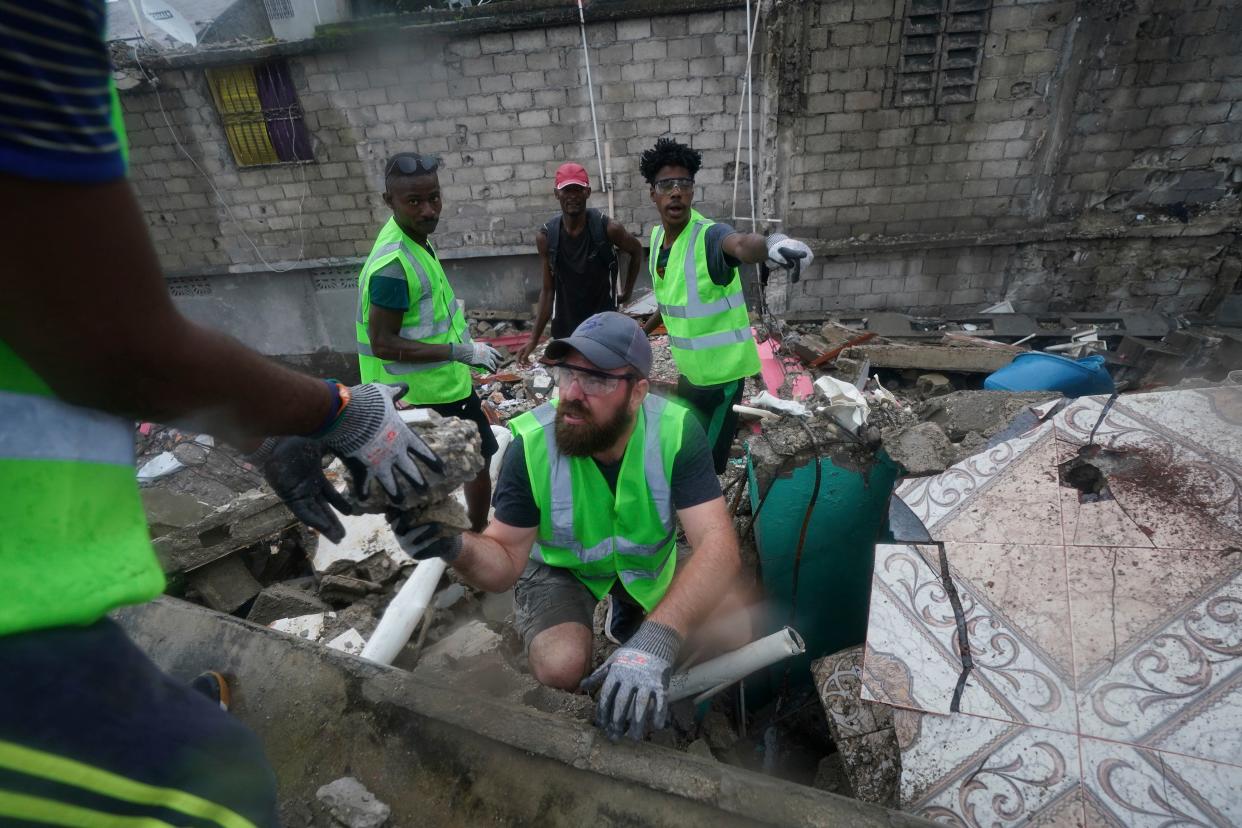 Canadian volunteer Randy Lodder helps search for people who may be trapped under the earthquake rubble the morning after Tropical Storm Grace swept over Les Cayes, Haiti, Tuesday, Aug. 17, 2021, three days after a 7.2 magnitude quake.