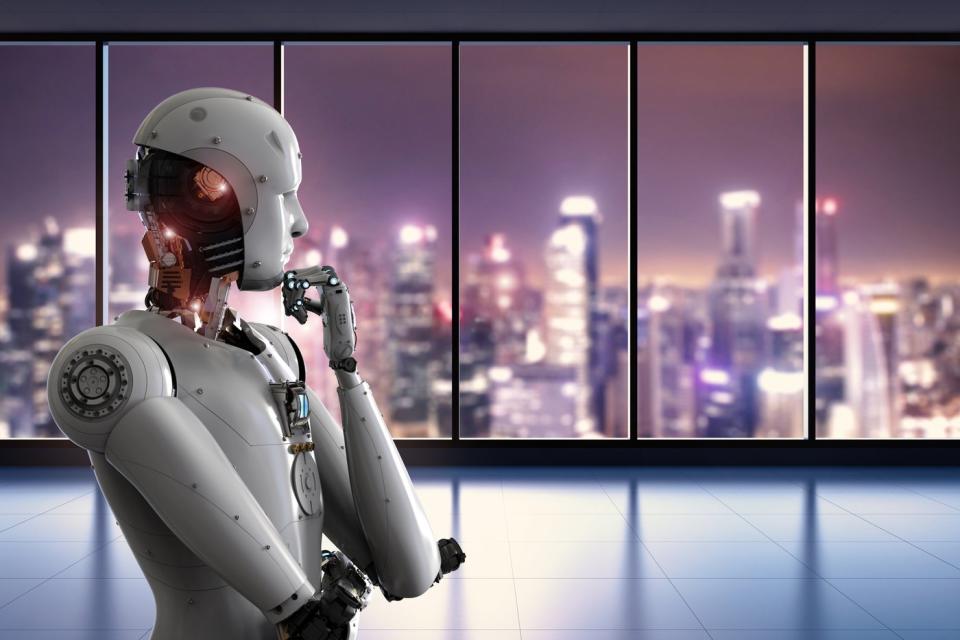 A robot gazes out of a window with a view of a metropolis at night.