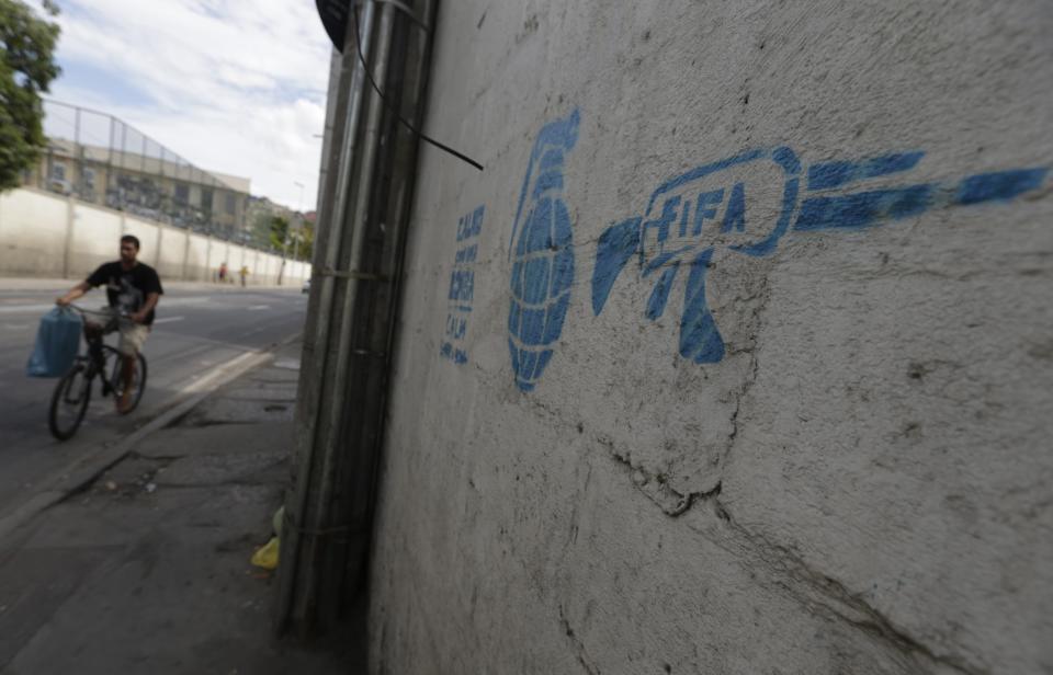 A man rides his bike past a graffiti referencing the 2014 World Cup in Rio de Janeiro May 23, 2014. Rio de Janeiro is one of the host cities for the 2014 World Cup in Brazil. REUTERS/Ricardo Moraes (BRAZIL - Tags: SPORT SOCCER WORLD CUP CIVIL UNREST)