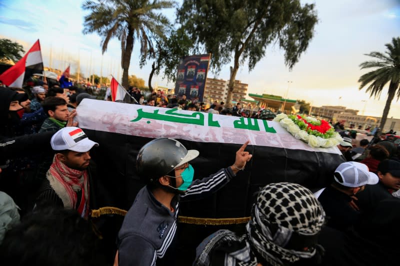 Mourners carry a mock coffin for an Iraqi demonstrator, who was killed during ongoing anti-government protests, at a symbolic funeral in Baghdad