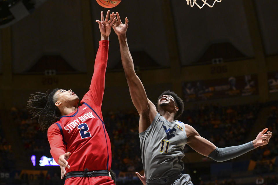 Stony Brook forward Frankie Policelli (2) and West Virginia forward Mohamed Wague (11) vie for a rebound during the second half of an NCAA college basketball game Thursday, Dec. 22, 2022, in Morgantown, W.Va. (William Wotring/The Dominion-Post via AP)