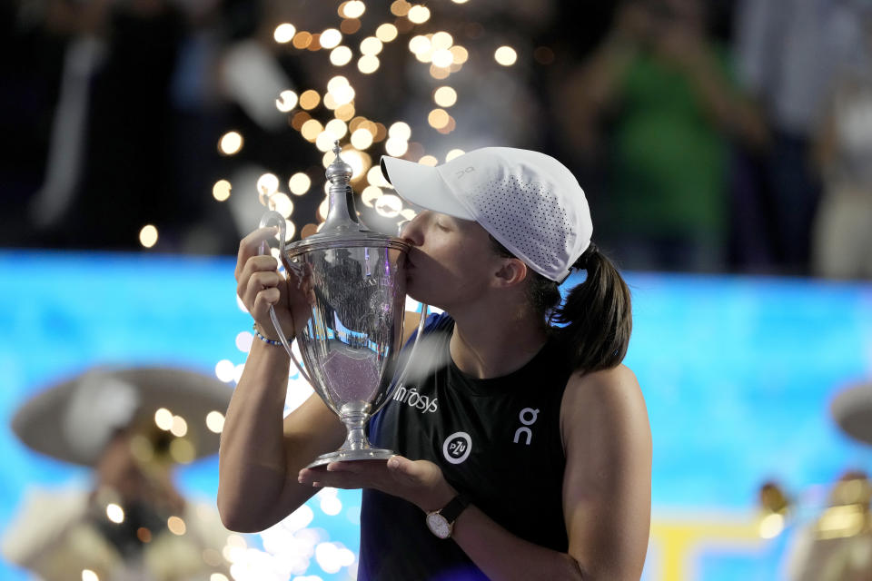 Iga Swiatek, of Poland, kisses her trophy after her victory over Jessica Pegula, of the United States, in the women's singles final of the WTA Finals tennis championships, in Cancun, Mexico, Monday, Nov. 6, 2023. (AP Photo/Fernando Llano)