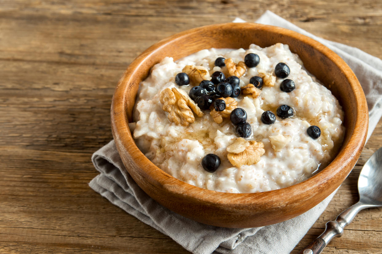 Oatmeal porridge with walnuts, blueberries and honey in wooden bowl with copy space - healthy rustic breakfast