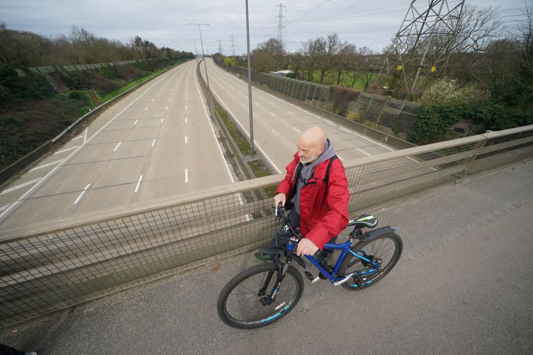 A man walks across the Parvis Road bridge in Byfleet, that crosses over a closed section of the M25 between Junctions 10 and 11, while a bridge is demolished and a new gantry is installed. Picture date: Saturday March 16, 2024.