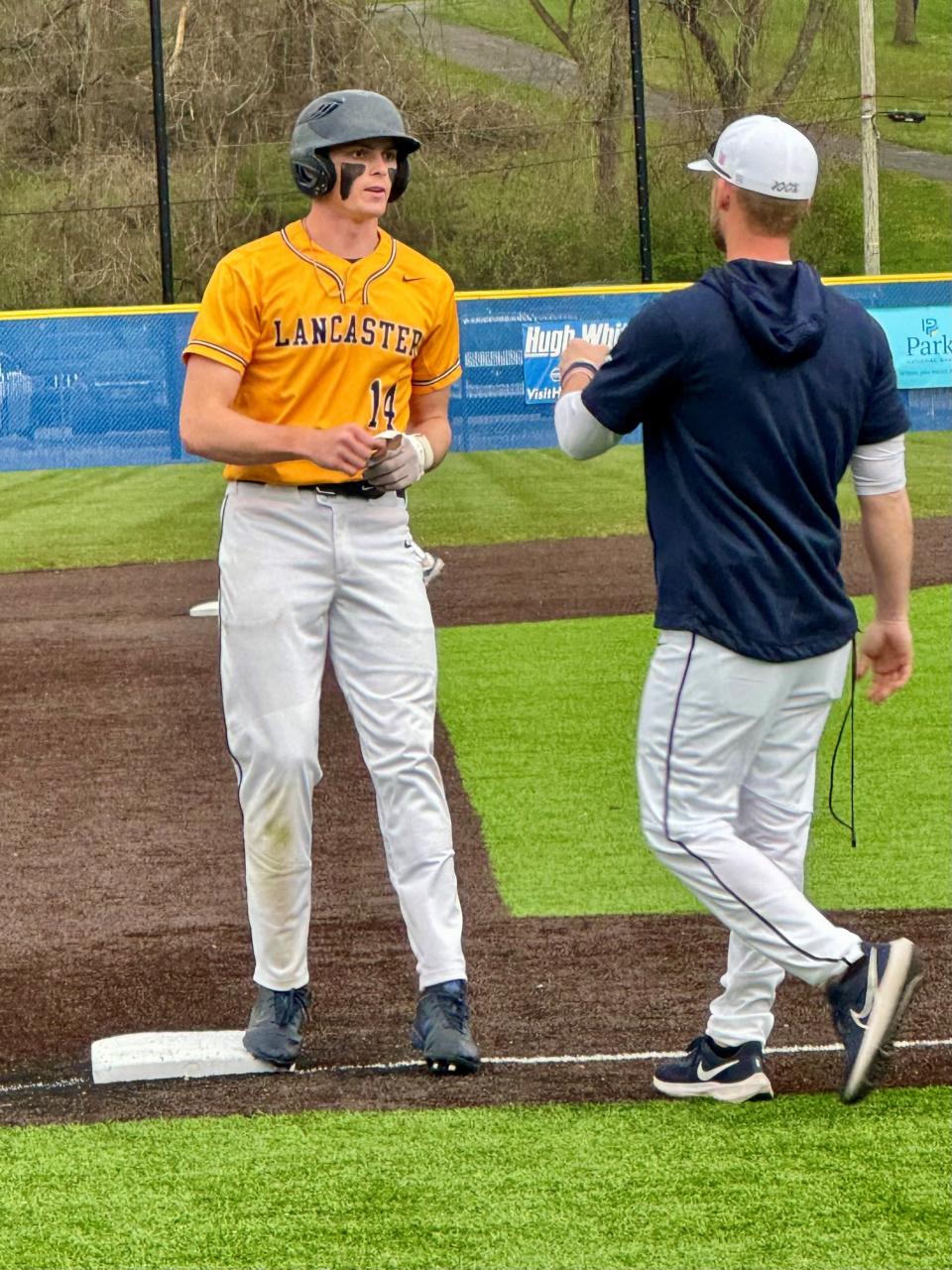 Lancaster baseball coach Corey Conn congratulates Hayden Allen after he reached third base during a recent game against Groveport at England Field.