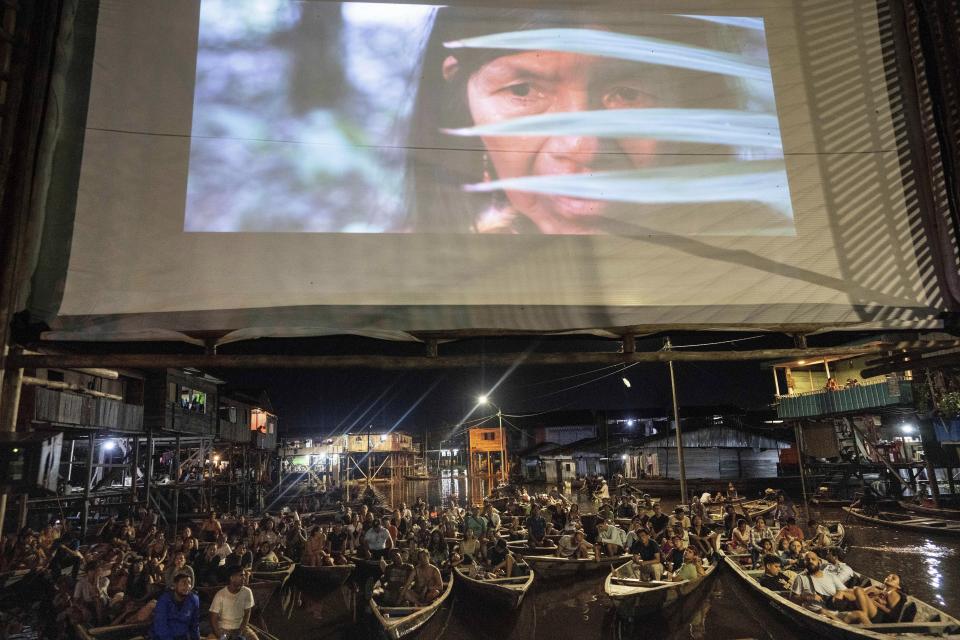 Los espectadores ven desde botes una película proyectada en una pantalla instalada sobre una estructura de madera durante el Festival de Cine Flotante Muyuna, que celebra los bosques tropicales, en el barrio Belén de Iquitos, Perú, el sábado 25 de mayo de 2024. (Foto AP/Rodrigo Abd )